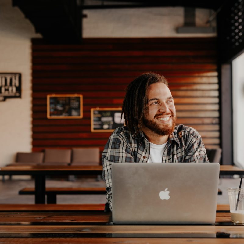 man in black and white plaid dress shirt sitting in front of silver macbook